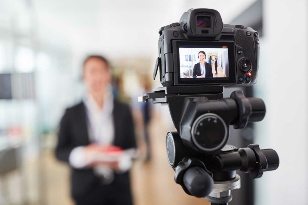 Camera in the foreground, with blurred background of a woman facing the camera